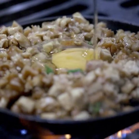 Chopped sisig on a hot cast iron plate with a raw egg yolk in the centre at Pinoy Tambayan