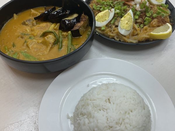 Bowl of kare kare in peanut sauce with aubergine, string beans and pechay, plate of pancit Malabon with prawns, quartered egg, crushed chicken skin and rice.
