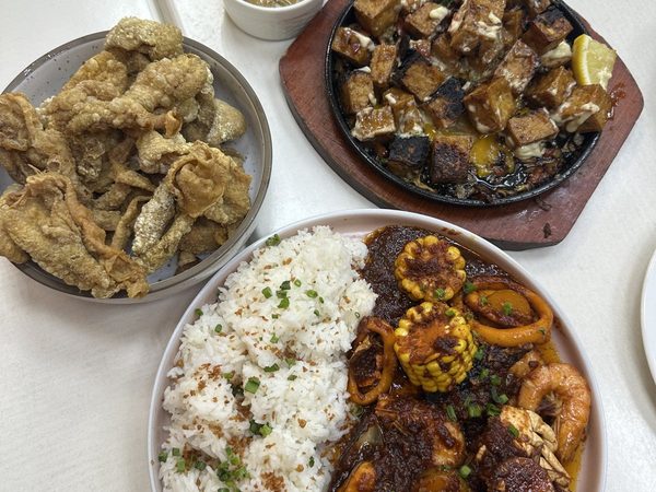 Overhead spread of crispy chicken skin, sizzling tofu with lemon, and a seafood platter of crab, squid and prawns in chilli sauce with garlic rice